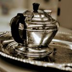 A stylish vintage silver teapot elegantly placed on a matching ornate serving tray, capturing timeless sophistication.