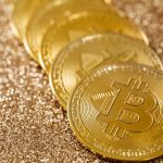 Close-up of golden Bitcoin coins on a shimmering glitter background, symbolizing digital currency's allure.