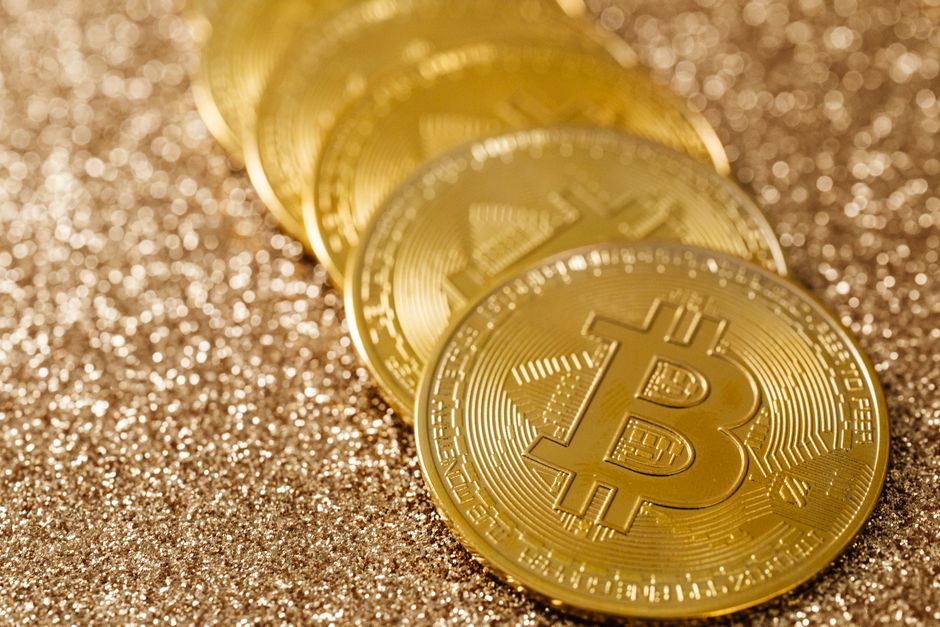 Gold 1 Close-up of golden Bitcoin coins on a shimmering glitter background, symbolizing digital currency's allure.